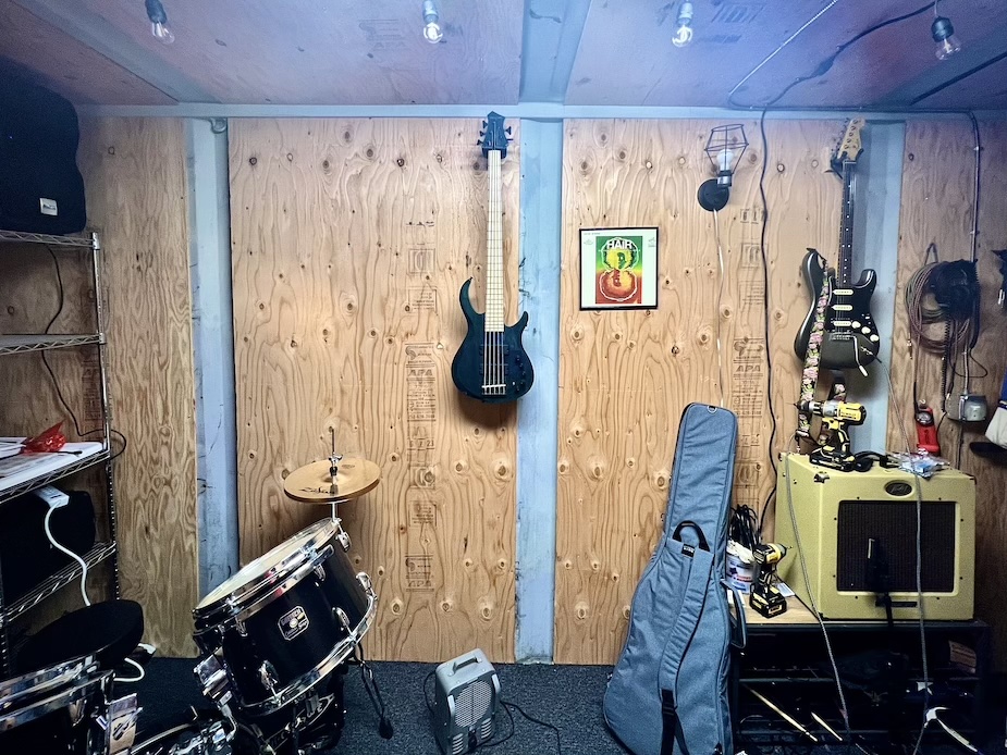 Guitar and bass on the walls of a rehearsal studio, drums visible on left